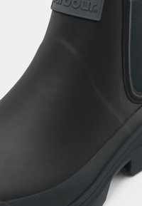 Μαύρη γυναικεία μπότες με λαστιχένια υφή, ελαστικά πλαϊνά πάνελ και ανάγλυφο λογότυπο στην επιφάνεια, με ανθεκτική λαστιχένια σόλα.