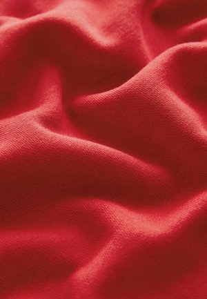 Rode stof met een zachte textuur, voorzien van zachte plooien en een glad oppervlak. Het materiaal lijkt lichtgewicht en rekbaar te zijn.
