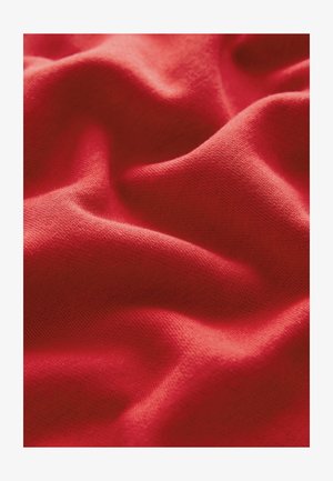 Červená látka s měkkou texturou, s jemnými záhyby a hladkým povrchem. Materiál působí lehce a elasticky.