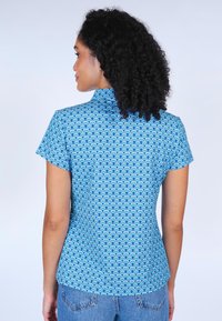 Blue short-sleeve shirt featuring a wave pattern in light and dark blue tones. Fitted design with a high collar and smooth texture.