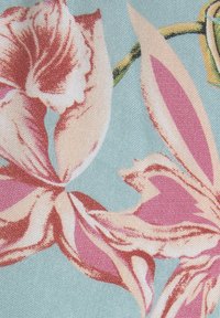 Květnatý textil s růžovými a krémovými květy na světle modrém pozadí. Textura vypadá tkaně a má hladký povrch.