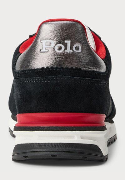 Juodų zomšinių sportinių batų su sidabriniu metaliniu kulno dangteliu, raudonais akcentais ir balta tarpine. "Polo" logotipas yra matomas ant nugaros.