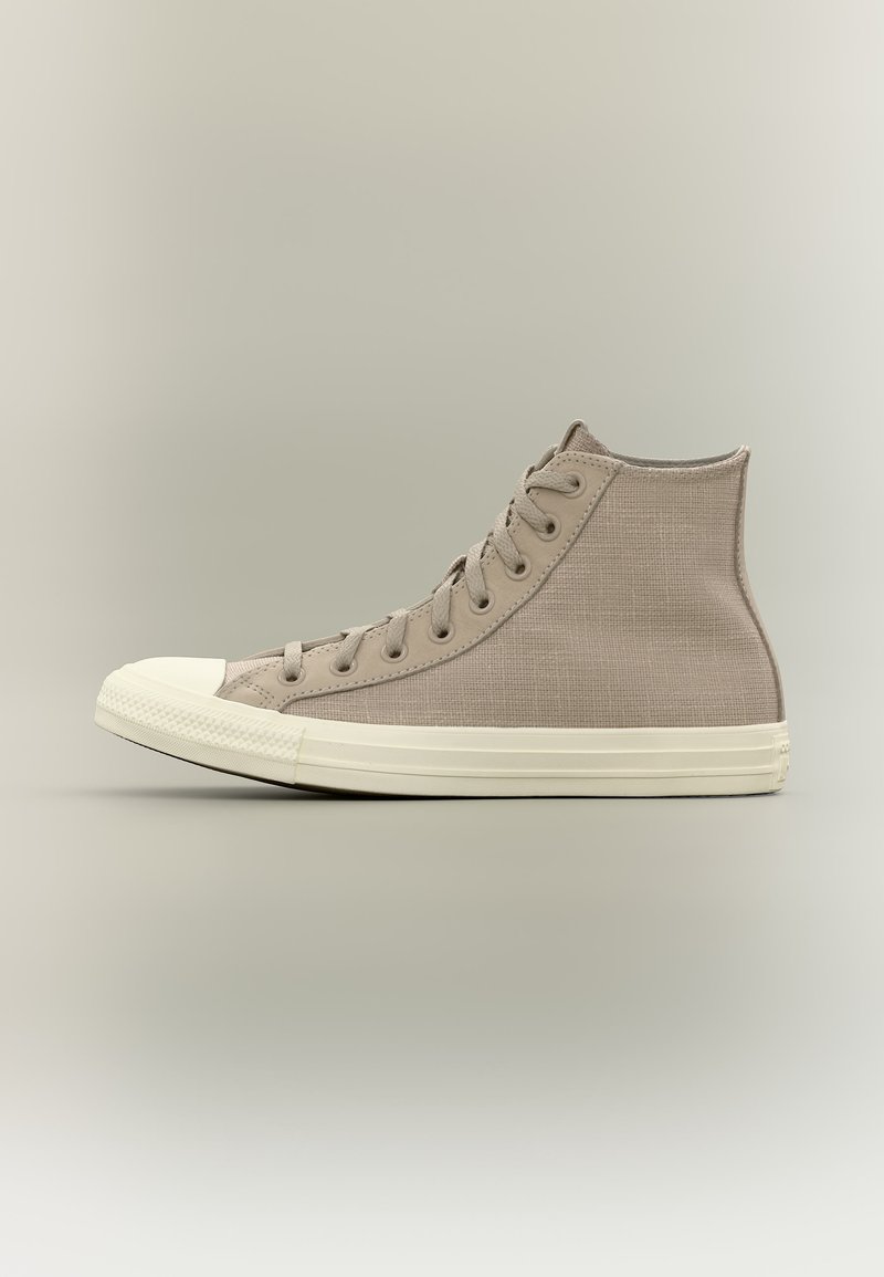 Μπεζ καμβάς sneaker με ψηλή γλώσσα, λευκή καουτσούκ σόλα και μύτη, σε ουδέτερο φόντο, από πλάγια όψη.