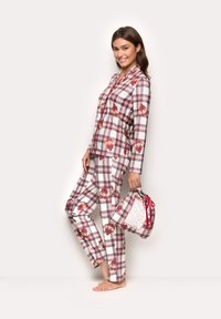 Plaid pajamas in white, red, and blue featuring a teddy bear pattern. Loose-fitting top and pants, paired with a matching drawstring bag.