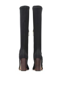 Bottes noires montantes en tissu texturé, avec un talon en bois épais, une fermeture éclair et une silhouette ajustée.