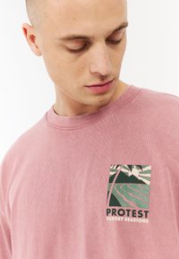 Roze katoenen t-shirt met een ronde hals en een grafisch logo in tinten groen en wit, dat een landschap afbeeldt, op de linkerborst.