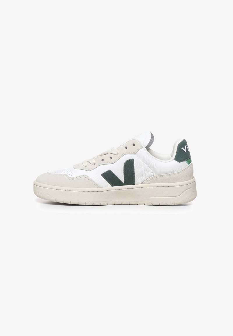 Zapatillas de cuero blanco con detalles en gamuza verde, suela de goma y un destacado logo en forma de "V". Presentan un diseño de caña baja y cordones redondos.