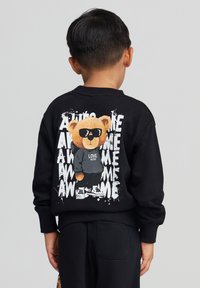 Felpa nera con un orso cartoon con occhiali da sole e cappuccio sul retro, circondato da testo splatter bianco che dice "AWESOME."