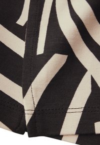 Svart och beige tyg med djärva, kantiga ränder. Närbild visar den släta texturen och subtila sömnadsdetaljer längs kanten.