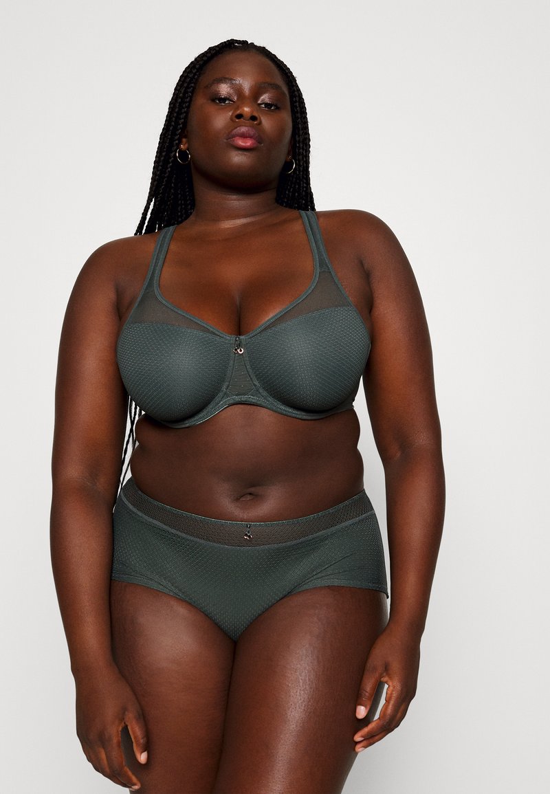 Dark green bra and matching briefs made of textured fabric, featuring mesh panels and a decorative accent in the center of the bra.