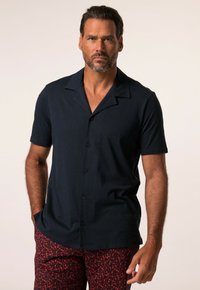 Mörk marinblå kortärmad skjorta med knappstängning och campkrage, slät textur och svarta knappar, i kombination med shorts med röd mönstring.