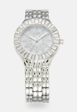 Montre en acier inoxydable argenté avec un cadran argenté scintillant, des index horaires rectangulaires, et un bracelet brillant à maillons avec des maillons arrondis.