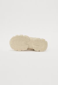 Krém színű sneaker talp, textúrált gumírozott felülettel, mély barázdákkal és bordákkal a tapadás és stabilitás érdekében.