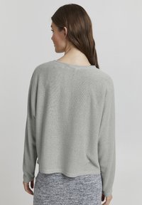 Ljust grå, texturerad stickad tröja med avslappnad passform och långa ärmar, med en bred halsringning och en kortad nederkant.