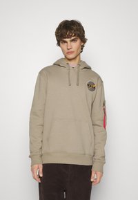 Felpa beige con logo NASA sul petto, coulisse regolabile e tasca con zip sul maniche sinistra con un tirante rosa.