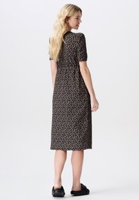 Schwarzes und beiges Blumen-Kleid mit kurzen Ärmeln, taillierter Taille und knöchellangem Saum. Glattes Material mit einem dezenten Musterdetail.