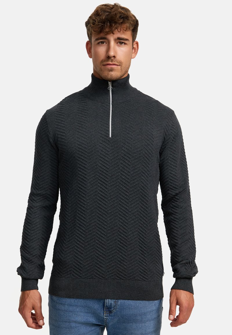 Dunkelgrauer Strickpullover mit hohem Kragen, der ein Fischgrätenmuster aufweist und einen halblangen Reißverschluss hat. Rippbündchen und Saum vervollständigen das Design.