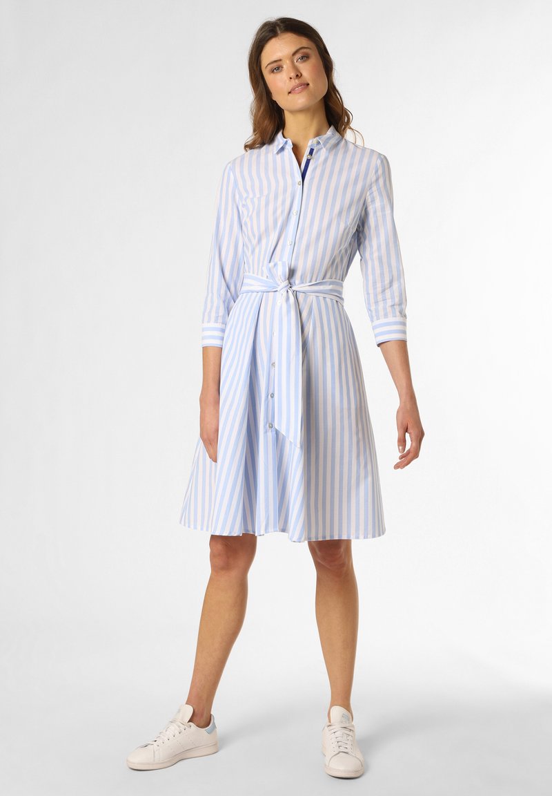 Blau-weiß gestreiftes Hemdkleid mit 3/4-Ärmeln, Knopfleiste, Taillengürtel und ausgestelltem Rock, kombiniert mit weißen Sneakers.