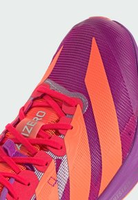 Close-up of purple and orange athletic shoe with pink laces and "ADIZERO" text on the tongue, showing mesh and synthetic materials.