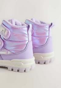 Lila Kinderstiefel mit glänzend, irisierender Oberseite, strukturiertem Lavendel-Einsatz, Klettverschlussriemen und dickem, weißem Sohlenprofil mit Rillen.