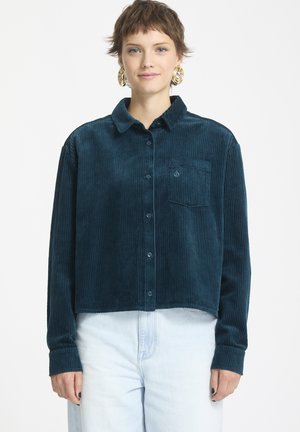 Teal corduroy overhemd met kraag, knoopsluiting aan de voorkant en één borstzak. Heeft verticale ribbels en lange mouwen. Verkorte stijl.