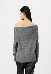 Pull gris décolleté en tricot doux et texturé avec un col et des poignets côtelés. Coupe décontractée avec des nuances variées et un motif subtil.