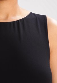 Černý bezrukávový oděv s hladkým, texturovaným materiálem, se zaobleným výstřihem a moderním těsným střihem.