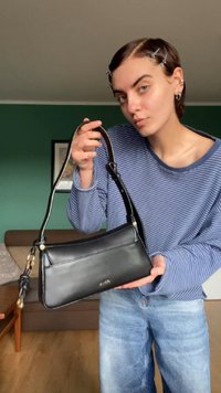 Borsa a tracolla nera in pelle con forma rettangolare, tracolla corta e hardware color oro. Presenta una superficie liscia e dettagli di cucitura minimi.