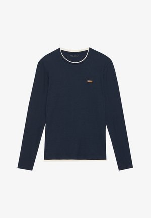 Long-sleeve navy ribbed shirt with a white collar, featuring a small brown label on the chest. Soft texture and relaxed fit.