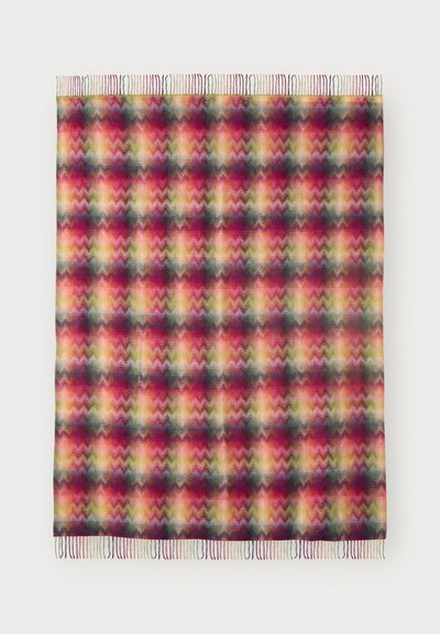 Farverigt vævet tæppe med et zigzag-mønster i nuancer af rød, gul, grøn og blå, med frynser i kanten for tekstur.