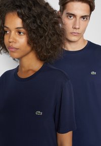Navy blauwe katoenen t-shirts met ronde hals, voorzien van een klein geborduurd groen krokodillenlogo, met een standaard pasvorm en een gladde textuur.