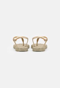 Sandali con zeppa color beige, con suola in juta intrecciata e cinturini trasparenti, che presentano un design minimalista e una costruzione aperta con punta piatta.