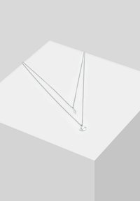 Sidabrinė sluoksniuota apyrankė su dviem grandinėlėmis, iš kurių viena turi minimalistinį akies pakabutį, o kita - elegantišką geometrinį akcentą.