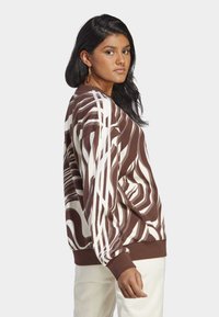 Sweater com padrão castanho e branco, com decote redondo, mangas longas e punhos canelados. Designs de ondas notáveis e riscas brancas contrastantes.