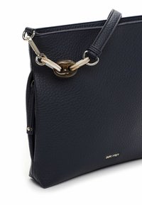Granatowa skórzana torebka o strukturalnej powierzchni, wyposażona w łańcuszkowy pasek z akcentem z żywicy oraz kieszeń na zamek po jednej stronie. Widoczna nazwa marki.