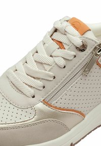 Lichtgrijze sneaker van textuurleer, met contrasterende oranje accenten, geperforeerd oppervlak en beige veters. Heeft een zijrits.