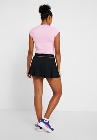 Paita pendek berwarna merah jambu dipadankan dengan skirt hitam yang mengembang. Pakaian ini mempunyai pinggang yang ketat, dengan aksen putih sempit di sepanjang pinggang.