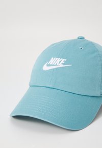 Világoskék Nike sapka texturált felületű szövetből. Az elején fehér hímzett logó található, és hajlított napellenzővel rendelkezik.