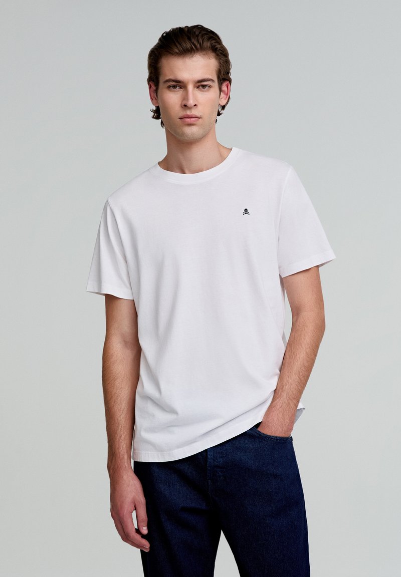 Witte katoenen t-shirt met een ontspannen pasvorm, korte mouwen en een ronde halslijn met een klein zwart schedellogo op de borst.
