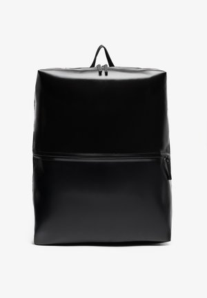 Mochila negra con un acabado brillante, forma rectangular, asa superior y un bolsillo con cremallera frontal para almacenamiento adicional.