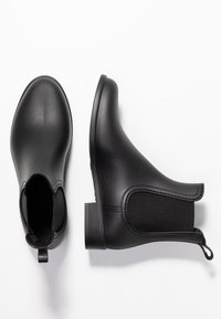 Svarta ankelskor med en slät, strukturerad läderöverdel, elastiska sidopaneler och en låg staplad klack för stabilitet.