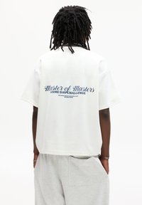 White oversized t-shirt with "Master of Masters Game Day Challenge" printed in blue on the back. Soft cotton fabric and relaxed fit.