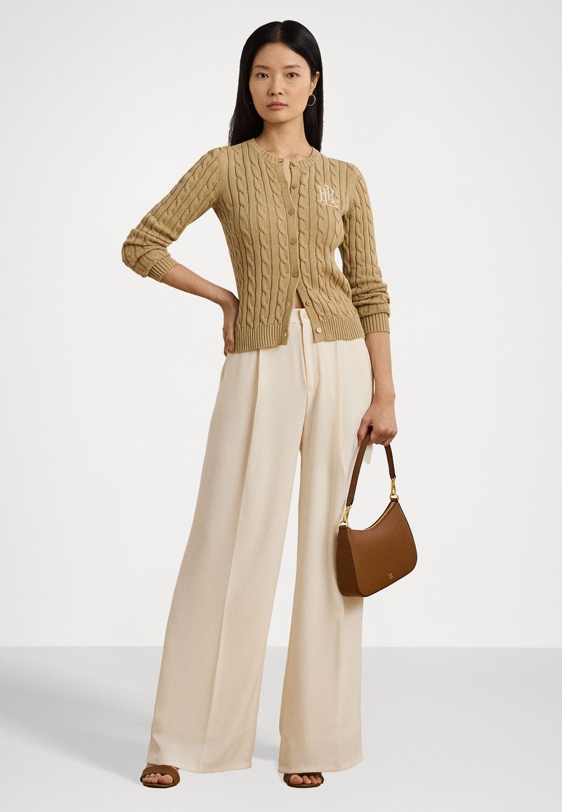 Beige Strickjacke mit Rundhalsausschnitt und Knöpfen, kombiniert mit weit geschnittenen cremefarbenen Hosen und einer braunen Handtasche. Schlichtes, strukturiertes Design.