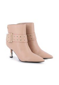 Botas de tobillo de cuero beige con punta afilada, hebilla decorativa y acentos de ojales, con un tacón metálico y una textura suave.