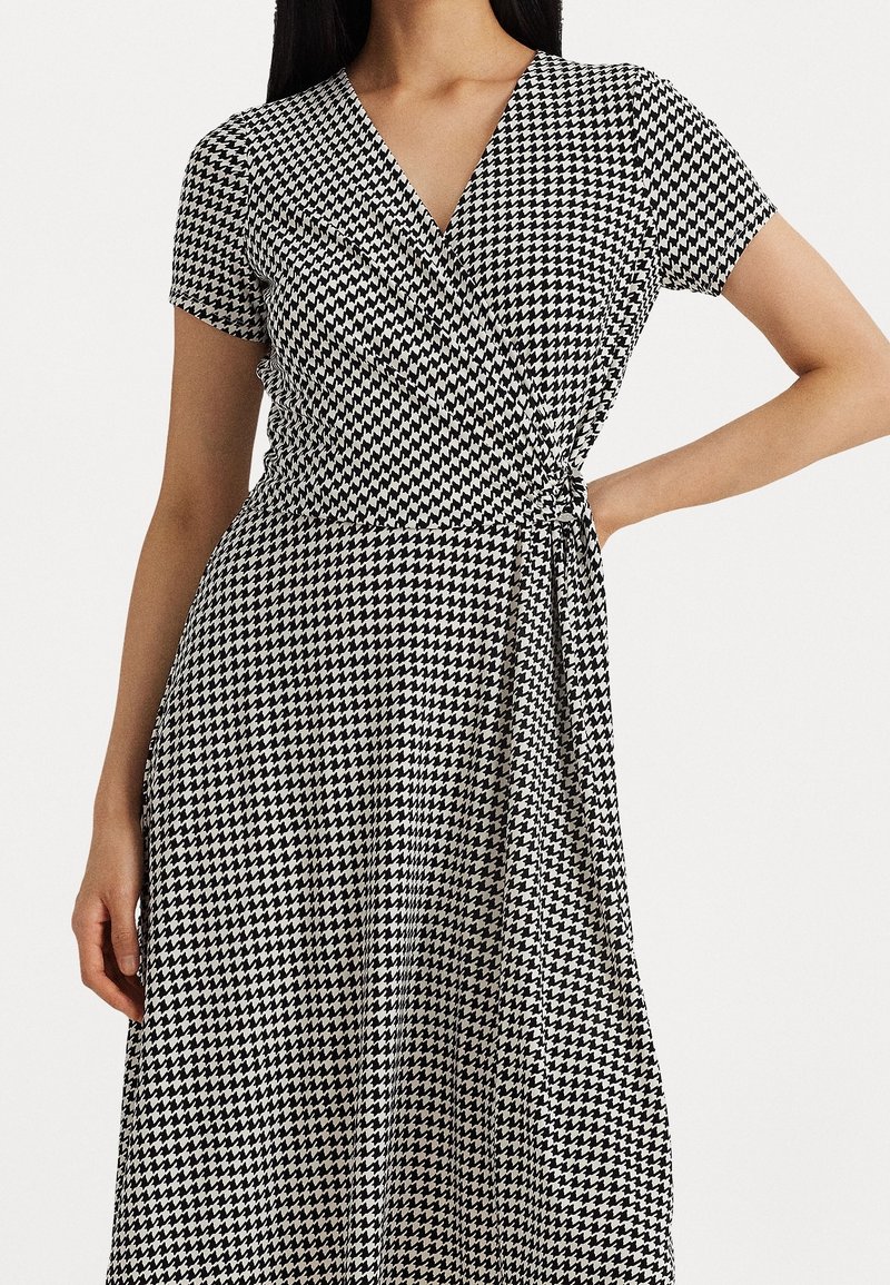 Sukienka w czarno-białą kratę houndstooth, z krótkimi rękawami, dekoltem w serek, wiązanym w pasie i zwiewnym materiałem.