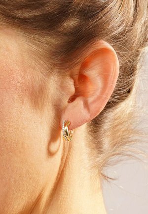 Goldene Creole mit verflochtenem Design und klaren Edelsteindetails. Die Ohringe besitzen eine elegante Oberfläche und eine moderne Form.