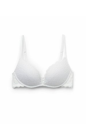 Witte kanten bralette met gepadde cups, geschulpte randen en verstelbare bandjes. Heeft een bloemenpatroon en een klein strikdetail in het midden.