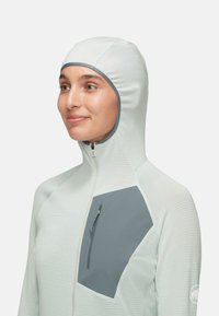 Ljusgrön huva-jacka med en strukturerad yta, som har en grå bröstficka och dragkedja. Slät tyg med en åtsittande design.