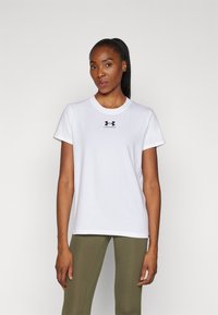 Bijela pamučna majica s okruglim vratom i kratkim rukavima, s malim crnim Under Armour logotipom na prsima.