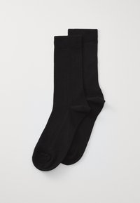 Čierne ponožky vyrobené z hladkého, elastického materiálu. Majú rebrovaný dizajn na vrchu a nenápadné logo na boku. Ploche spoje na prstoch.